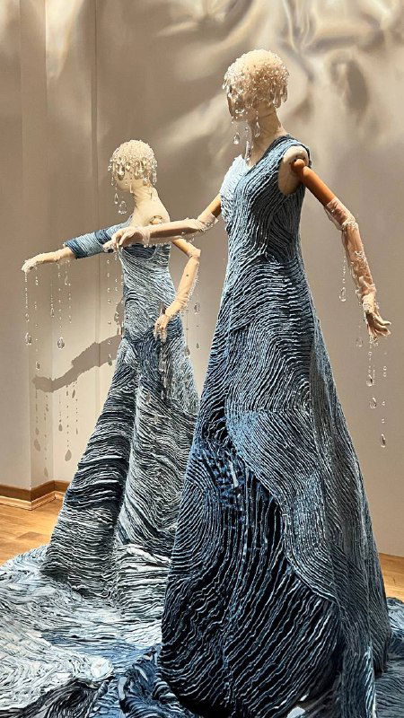 Красный костюм-манекен на подиуме: яркий вертикальный акцент, контрастный цвет и сложное сочетание материалов в образе.