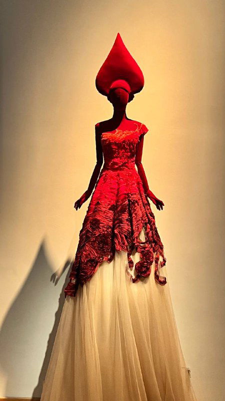 Ряд белых манекенов в изящных нарядах, украшенных жемчужными и текстильными элементами, на фоне подвешенных украшений.