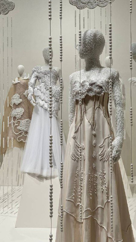 Инсталляция с белыми манекенами и подвесными элементами, создающая ощущение снижения и дождя декоративных деталей в пространстве.