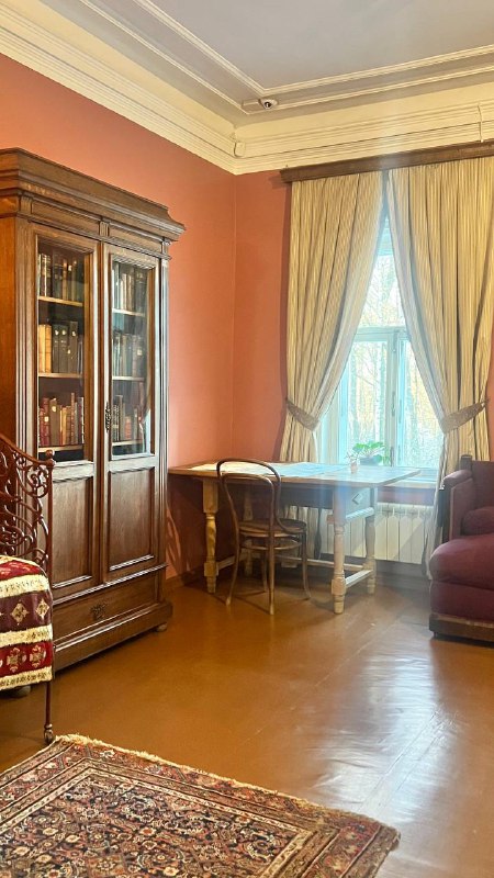 Уютный музейный кабинет с книжным шкафом, столиком у окна и креслом; бытовой интерьер, который создаёт представление о домашней жизни Чайковского.