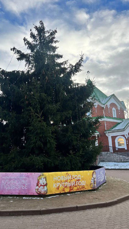 Большая городская ёлка на площади Клинского подворья без игрушек, пустая праздничная инсталляция и почти абсурдная сцена розничного оформления вокруг.