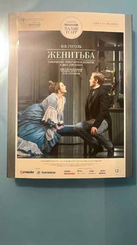 Афиша спектакля «Женитьба» на стене театра: постер с актёрами, название и указание постановки — знак программы вечера на Ордынке.