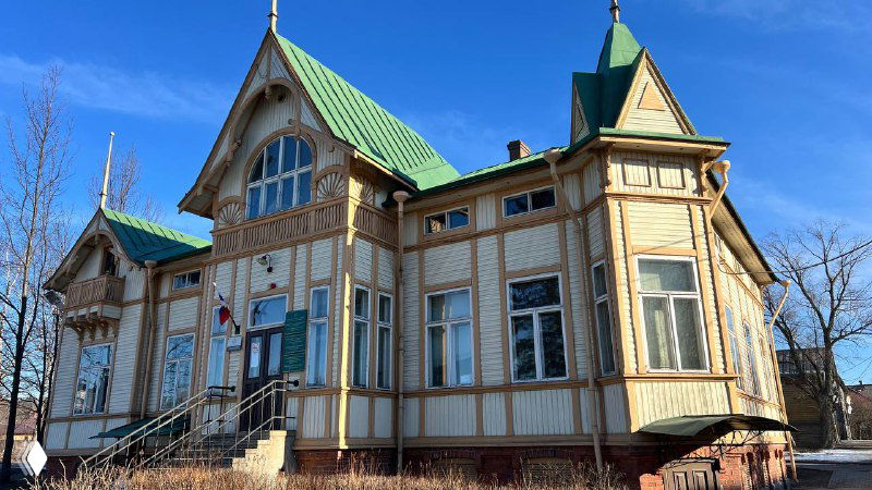 Деревянный особняк с резным декором и зелёной крышей — пример аутентичной финской застройки Сортавалы, на ярком солнечном фоне.