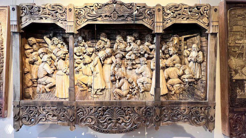 Большое многочастное панно с резьбой, множество фигур и сцен в одном полотне, детальная декоративная рамка и насыщенный сюжет.