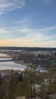 Панорамный вид со смотровой на долину и ледяные участки Ладоги, селение внизу и дальняя линия леса на горизонте.