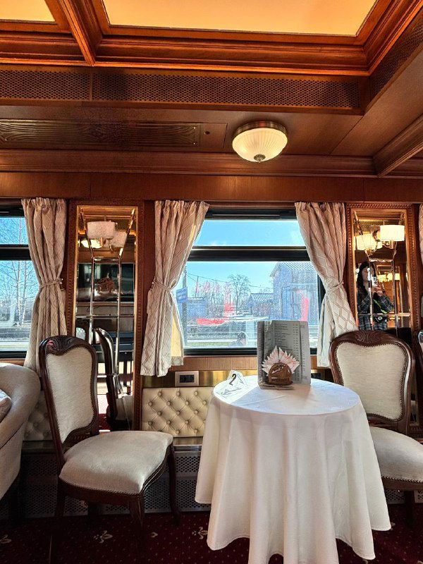 Ещё один ресторанный уголок с круглыми столиками и креслами у окон; свет и текстуры древесины создают ретро‑настроение.