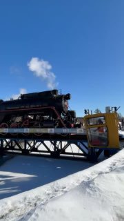 Паровоз на разворотном круге в снегу; машина стоит на платформе поворотного механизма, видно основание круга и зимний пейзаж.