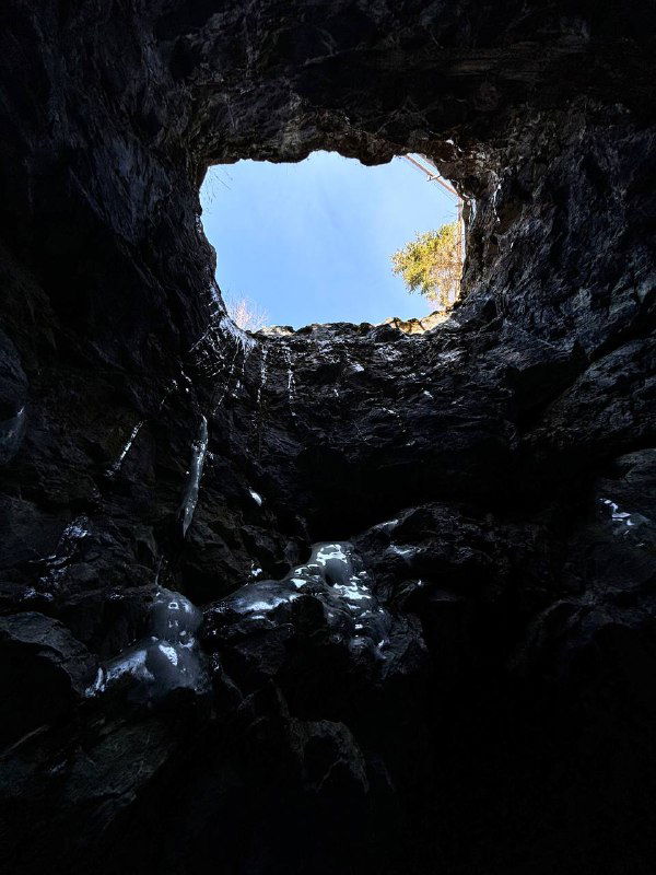 Вид из провала в пещере вверх: обрамлённое небо и край мраморной стенки, ощущение глубины и подземного пространства Рускеалы.