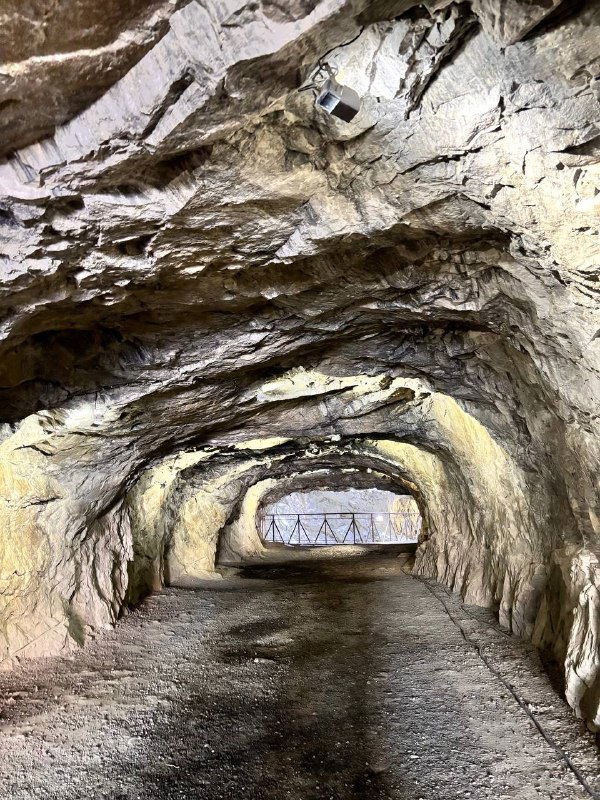 Внутренний тоннель или проход в мраморе с искусственным освещением и арочной формой, пол тоннеля влажный и светящейся подсветкой.