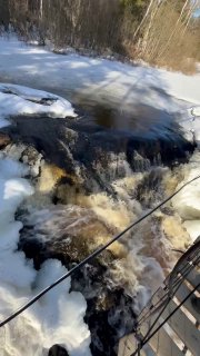 Кусок бурной реки Тохмайоки в районе Ахвенкоски с тёмной пеной, быстрым течением и снежными полями на берегах, контраст воды и льда.