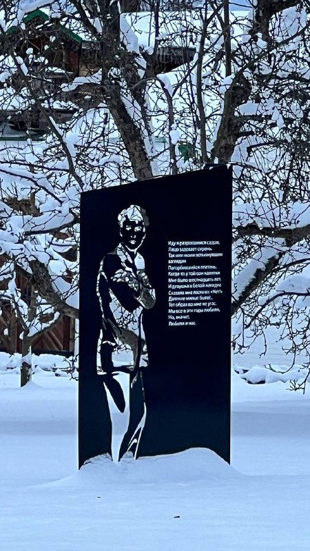 Памятная стела или чёрная табличка с силуэтом и текстом в снегу на фоне деревьев — музейная экспозиция на открытом воздухе.
