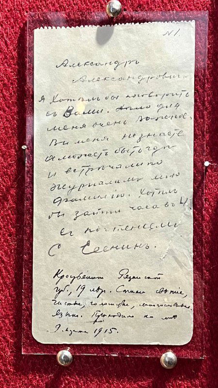 Хранительская витрина с рукописной заметкой под стеклом: крупный план старой бумаги с автографом и печатной подписью в экспозиции.