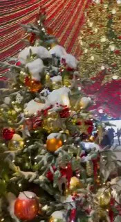 Фрагмент украшенной ели под шатром: ветки в снегу, игрушки и огоньки на переднем плане, атмосферная новогодняя детализация в Туле.