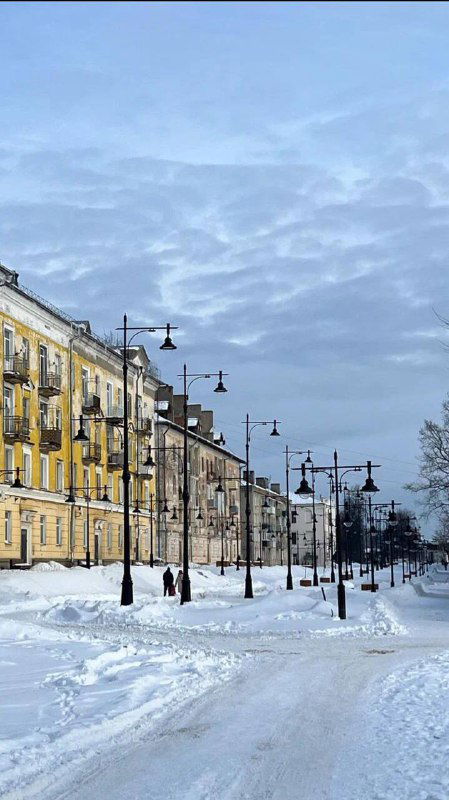 Пустая зимняя улица Углича с рядами фонарей и желтыми домами, снег под ногами и спокойная городская перспектива.