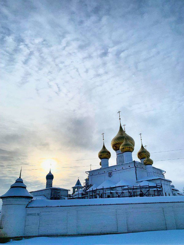 Силуэты золотых куполов на фоне драматичного неба в Угличе, вид с набережной и приглушённое зимнее освещение.