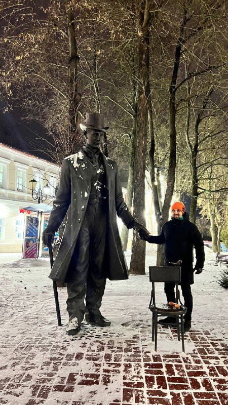 Человек рядом со статуей высокого «Витебского великана» Фёдора Махнова ночью в снегу; заметна контрастная композиция памятника и посетителя.