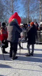 Толпа посетителей на площади фестиваля рядом со сценой: люди в тёплой одежде, съёмочная группа и активность на свежем воздухе.