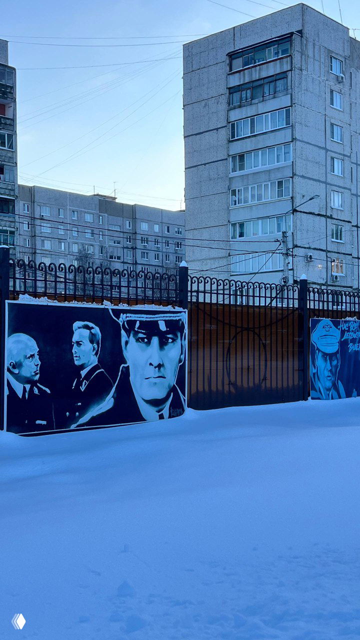 Уличная стена с граффити и портретами персонажей из «Семнадцати мгновений весны» на фоне многоэтажек — наружная часть музейного комплекса в зимнем окружении.