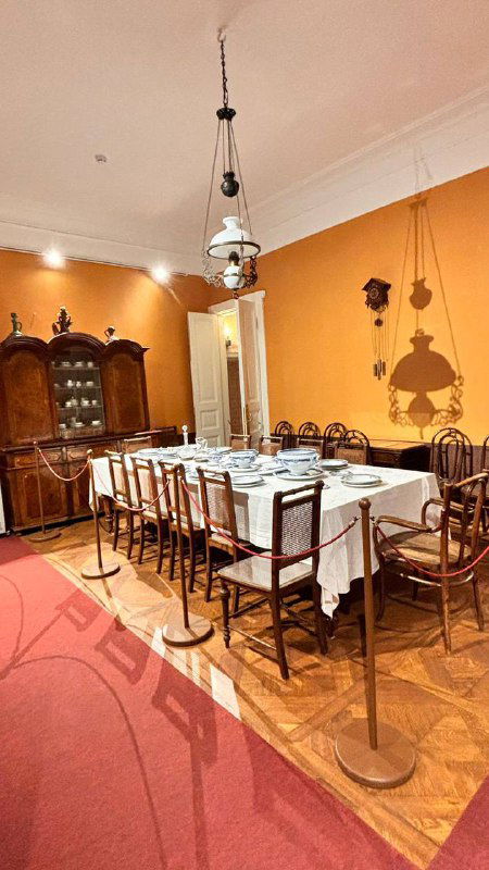 Интерьер столовой в доме-музее Толстого: длинный сервированный стол, старинные стулья и буфет на тёплом фоне комнаты.