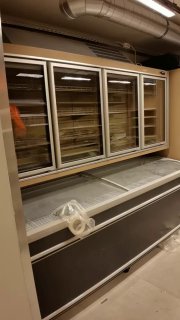 Холодильные витрины и морозильные лари внутри помещения на момент осмотра: пустые секции и подготовка к выкладке товаров перед открытием.