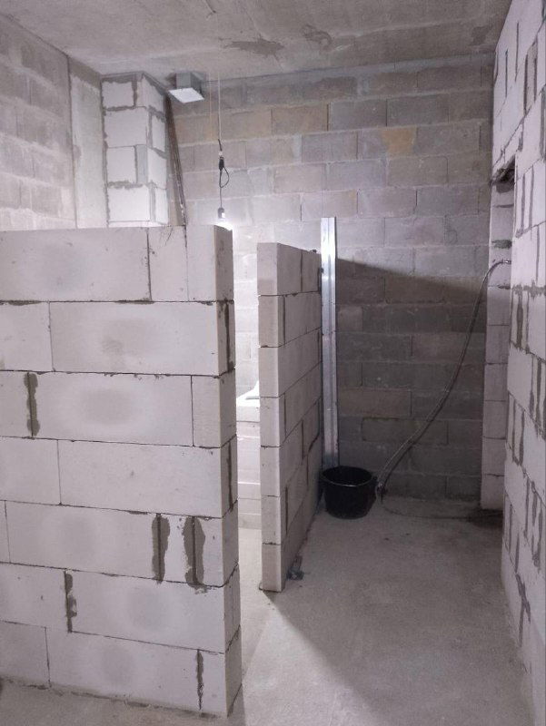 Возведение внутренних перегородок из блоков в новостройке: частично собранные стены, явно видны проёмы для дверей и заготовки коммуникаций внутри помещения.