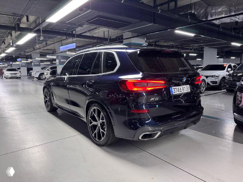 Задняя часть BMW X5 30d xDrive MSport в паркинге: вид на фонари, выхлопные патрубки и форму кузова в профиль сзади.