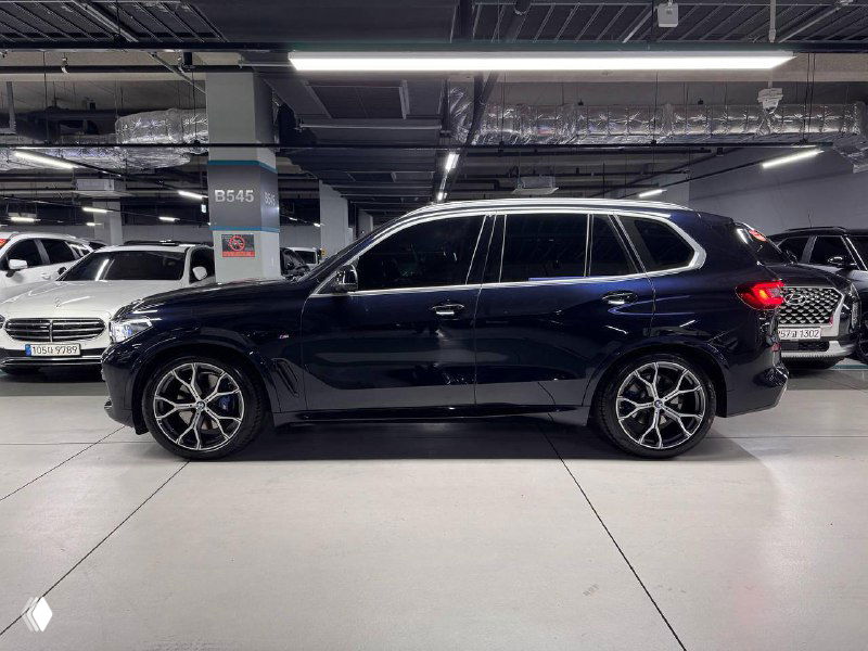 Боковой профиль чёрного BMW X5 30d xDrive MSport в гаражном шоуруме, вид в полный рост с акцентом на колёса и силуэт автомобиля.