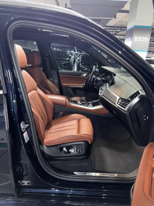 Переднее пассажирское кресло BMW X5 30d xDrive MSport в открытом положении, коричневая кожа и регулировки сиденья на показанном фоне салона.