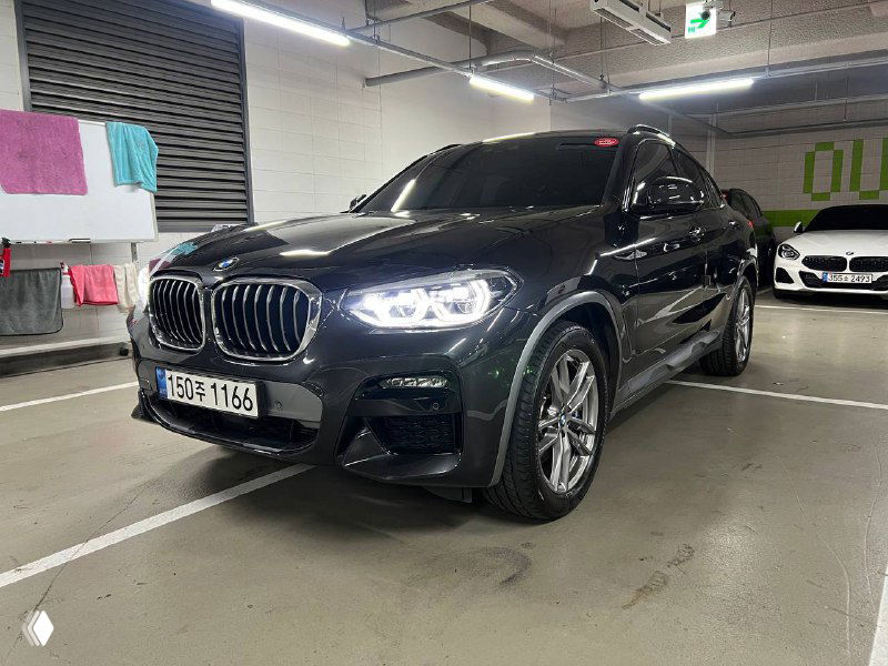 Передний угловой вид BMW X4: клиренс, радиаторная решётка и фары в паркинге, показывающие общий внешний вид и целостность передней части.