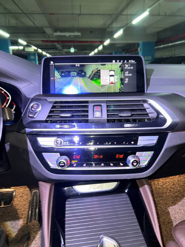 Центральная консоль и мультимедийный экран BMW X4: крупный план панели управления климатом и мультимедиа, состояние кнопок и экрана.