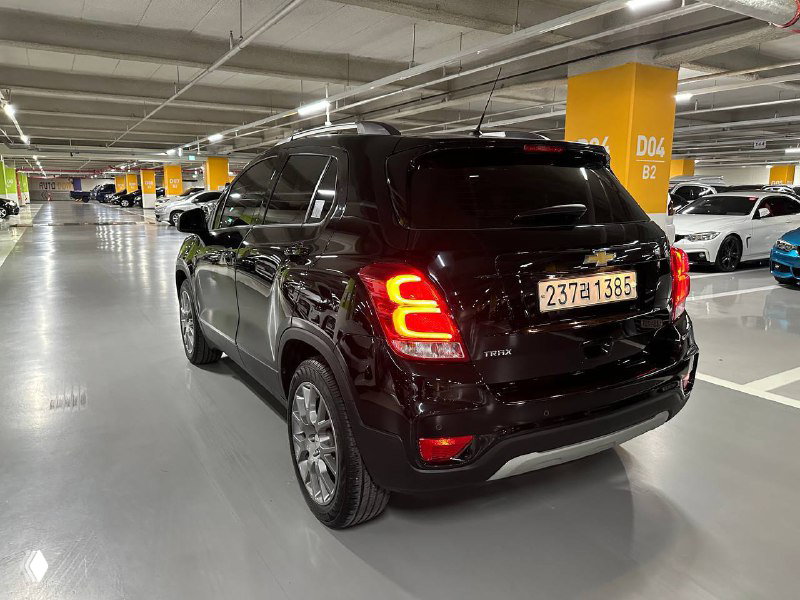 Задняя часть Chevrolet Trax 2020 на парковке — включены фонари, видна форма багажника и состояние заднего бампера.