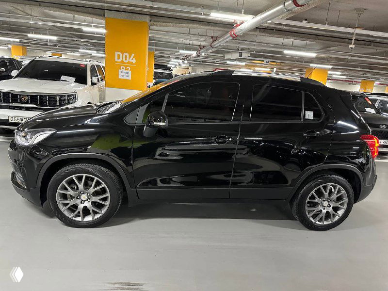 Черный Chevrolet Trax 2020, боковой вид с противоположной стороны — виден лак, колёсные арки и линия двери на ровной парковке.