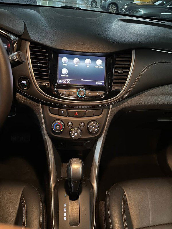 Центральная консоль и мультимедийный дисплей Chevrolet Trax 2020 — кнопки управления климатом и селектор коробки передач видны крупным планом.