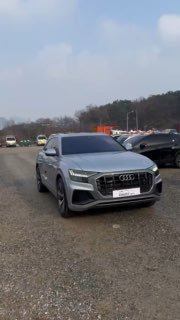 Audi Q8 50 TDI Quattro Premium серебристого цвета, общий вертикальный кадр на стоянке в Южной Корее, вид спереди‑сбоку, рядом другие машины.