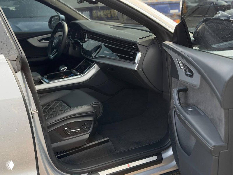 Интерьер Audi Q8: пассажирская часть салона, дверная панель, сиденье и детали отделки — чёрная кожа и декоративная прострочка на сиденьях.