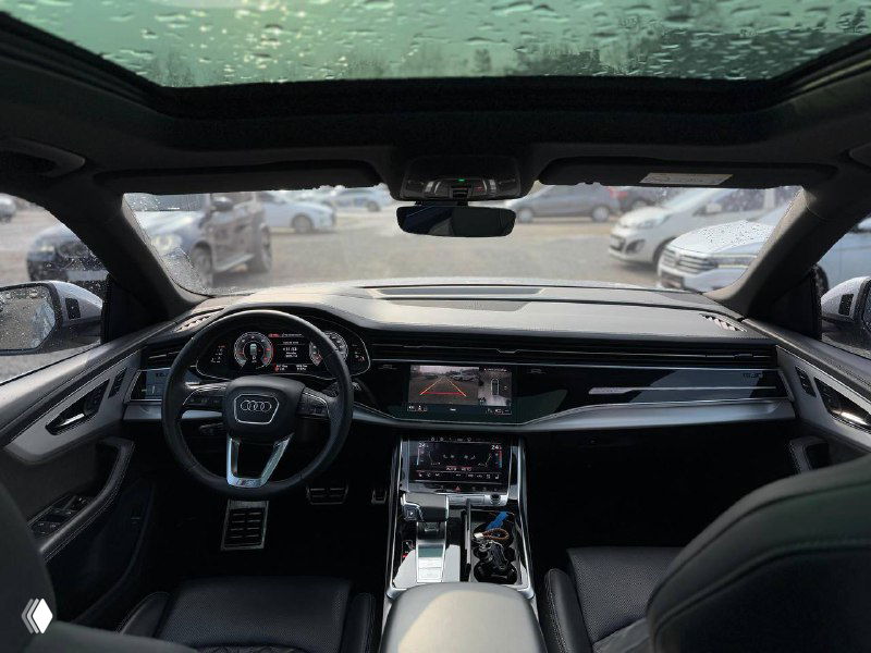 Панорамный вид на торпедо и лобовое стекло Audi Q8, заметна панорамная крыша, цифровая приборная панель и ухоженный интерьер салона.