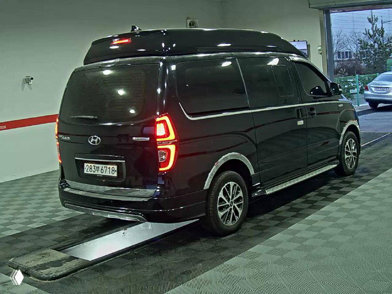 Задняя часть Hyundai Grand Starex Limousine: фонари, багажная дверь и общий вид сзади, автомобиль на рампе в автосалоне.