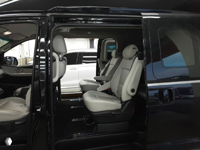 Салон Hyundai Grand Starex Limousine: передние и средние сиденья белого/светлого тона, вид открытой боковой двери и пространства для пассажиров.