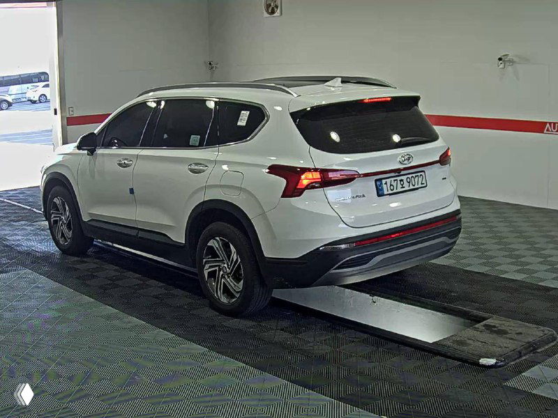 Hyundai Santa Fe белого цвета в закрытом боксе, ракурс сзади и слева, видна геометрия кузова и номерные рамки на автомобиле