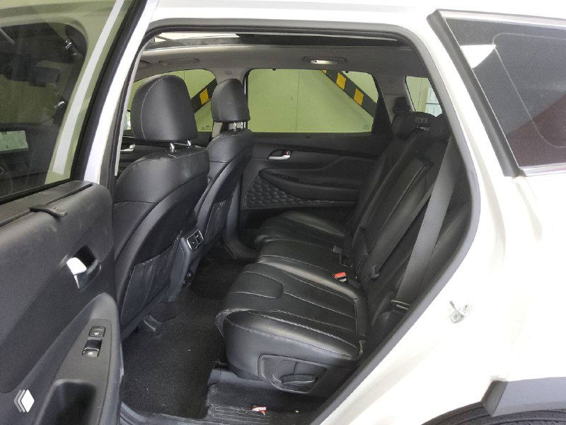 Салон Hyundai Santa Fe — открытая задняя дверь, видно второй ряд сидений из чёрной кожи и пространство для пассажиров с акцентом на комфорт