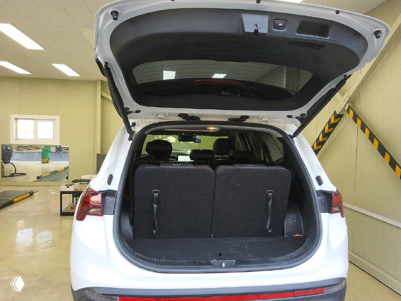 Открытый багажник белого Hyundai Santa Fe, видно грузовое отделение и заднюю часть салона, складенные сиденья частично подняты