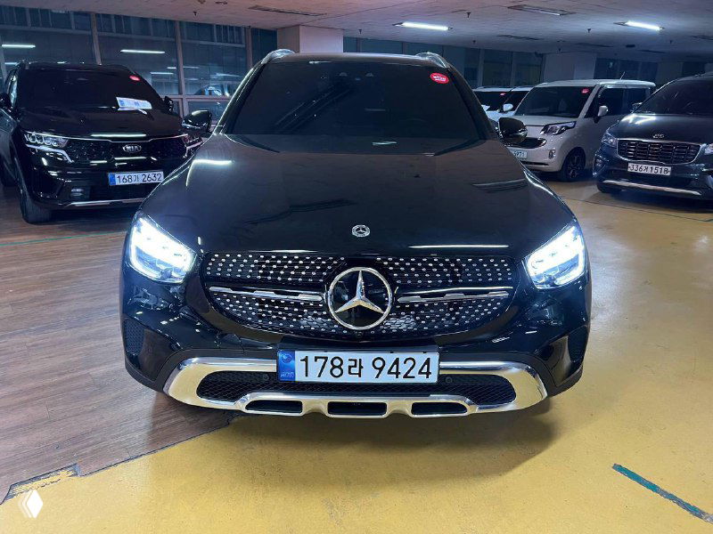 Фронтальный вид Mercedes GLC 220 D 4Matic в закрытом паркинге, хорошо видна передняя решетка, эмблема Mercedes и светодиодные фары.