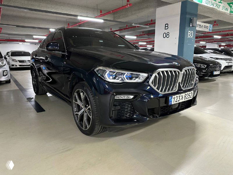 BMW X6 40i xDrive MSport вид спереди-сбоку на парковочном месте, чёрный кузов с отражениями, хорошо видны фары и диски