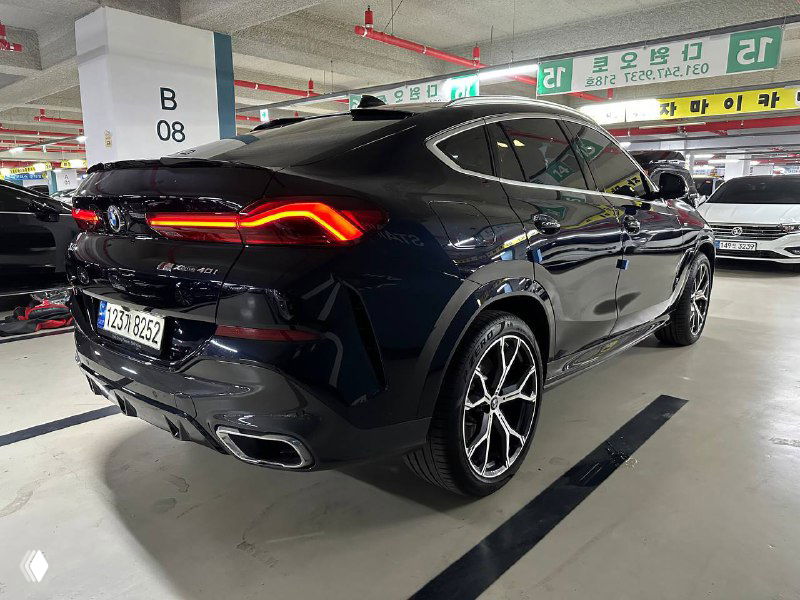 Задний три четверти BMW X6 40i xDrive MSport тёмного цвета с заметной задней оптикой и двойными патрубками выхлопа на парковке