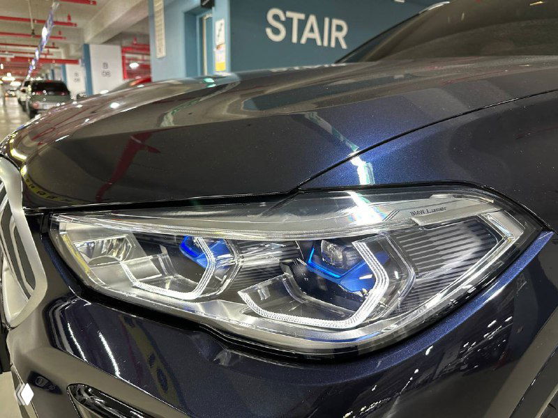 Крупный план лазерной оптики головной фары BMW X6 с синими акцентами в модуле, видно конструкцию и детали светодиодов