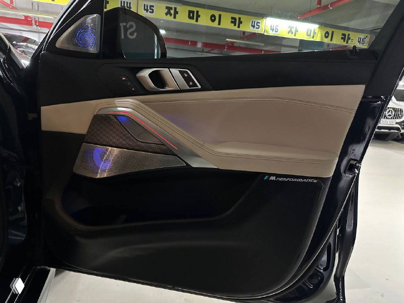 Внутренний ракурс двери и порога BMW X6 с акцентом на элементы управления и подсветку, крупный план качества материалов и швов