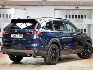 Вид сзади Honda CR‑V Touring 6‑го поколения: багажник, задние фонари и нижний диффузор на фоне автосалона, тёмно‑синий кузов.