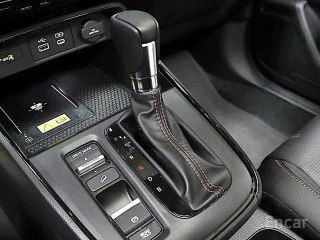 Фрагмент салона Honda CR‑V: селектор коробки передач, консоль с кнопками и отделка из тёмной кожи с декоративной прострочкой.