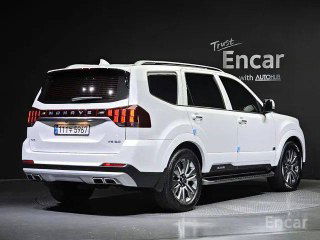 Белый Kia Mohave Masters, трёхчетвертной вид сзади слева на студийном фоне, видно оформление задней части кузова, фонари и диски автомобиля.