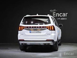 Kia Mohave Masters белого цвета, вид строго сзади на студийном фоне, подсвеченные задние фонари и номера на выставочном стенде Encar.